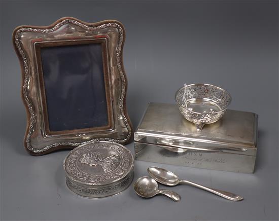 A silver cigarette box, a continental embossed silver box, a silver photo frame, a silver caddy spoon, silver dish and spoon.